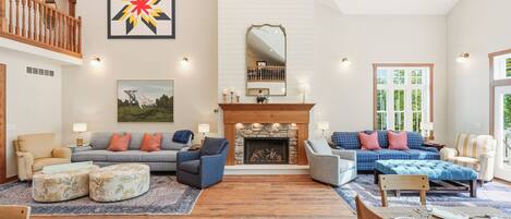 A spacious living room with a fireplace, multiple seating options, and a large window.