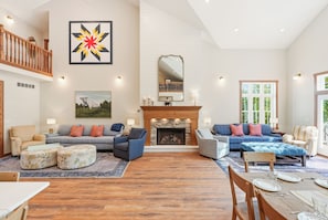 A spacious living room with a fireplace, multiple seating options, and a large window.