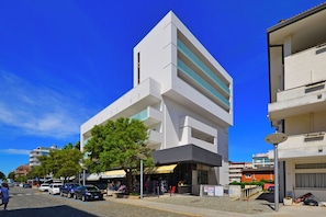 A modern building with a flat facade, large windows, and a tree in front. - Holiday Home Just 50m From the Beach (Lignano Sabbiadoro)