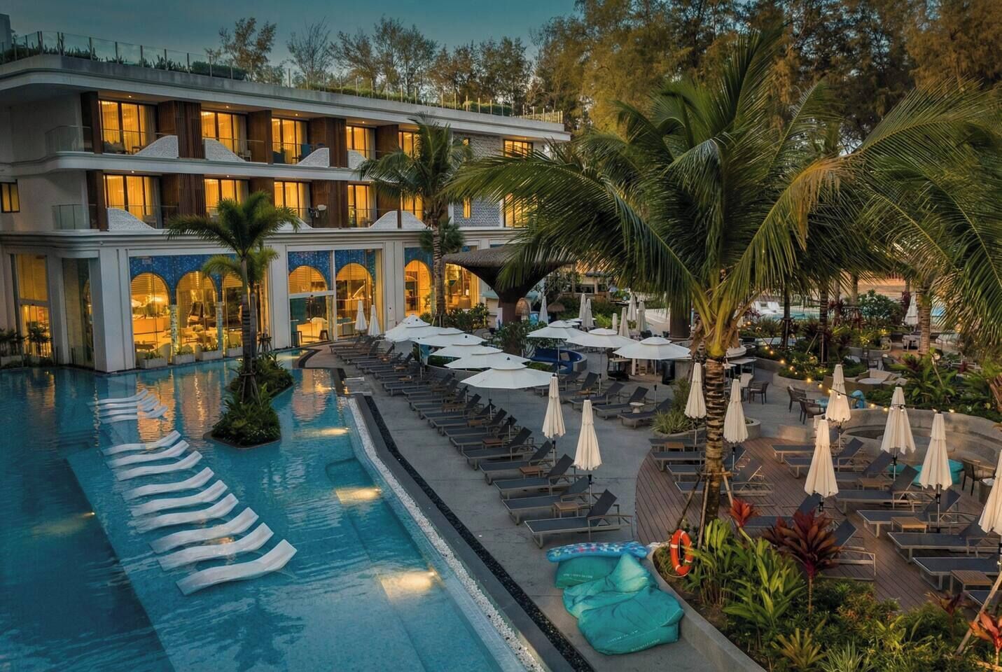 Un hôtel doté d’une piscine, de chaises longues et de palmiers.