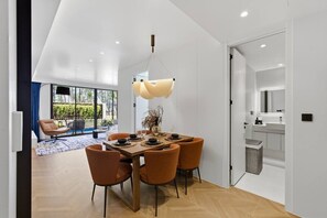 A modern dining area with a wooden table, six chairs, and a hanging light fixture. - Private Pool/ 200 m to the Beach Design Apartment (Choeng Thale)