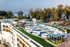 Ein Hotel mit mehreren Schwimmbecken, einem Tennisplatz und Meerblick.