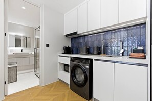 A modern kitchen with a built-in washer, a coffee maker, and a kettle on the countertop. - Private Pool/ 200 m to the Beach Design Apartment (Choeng Thale)