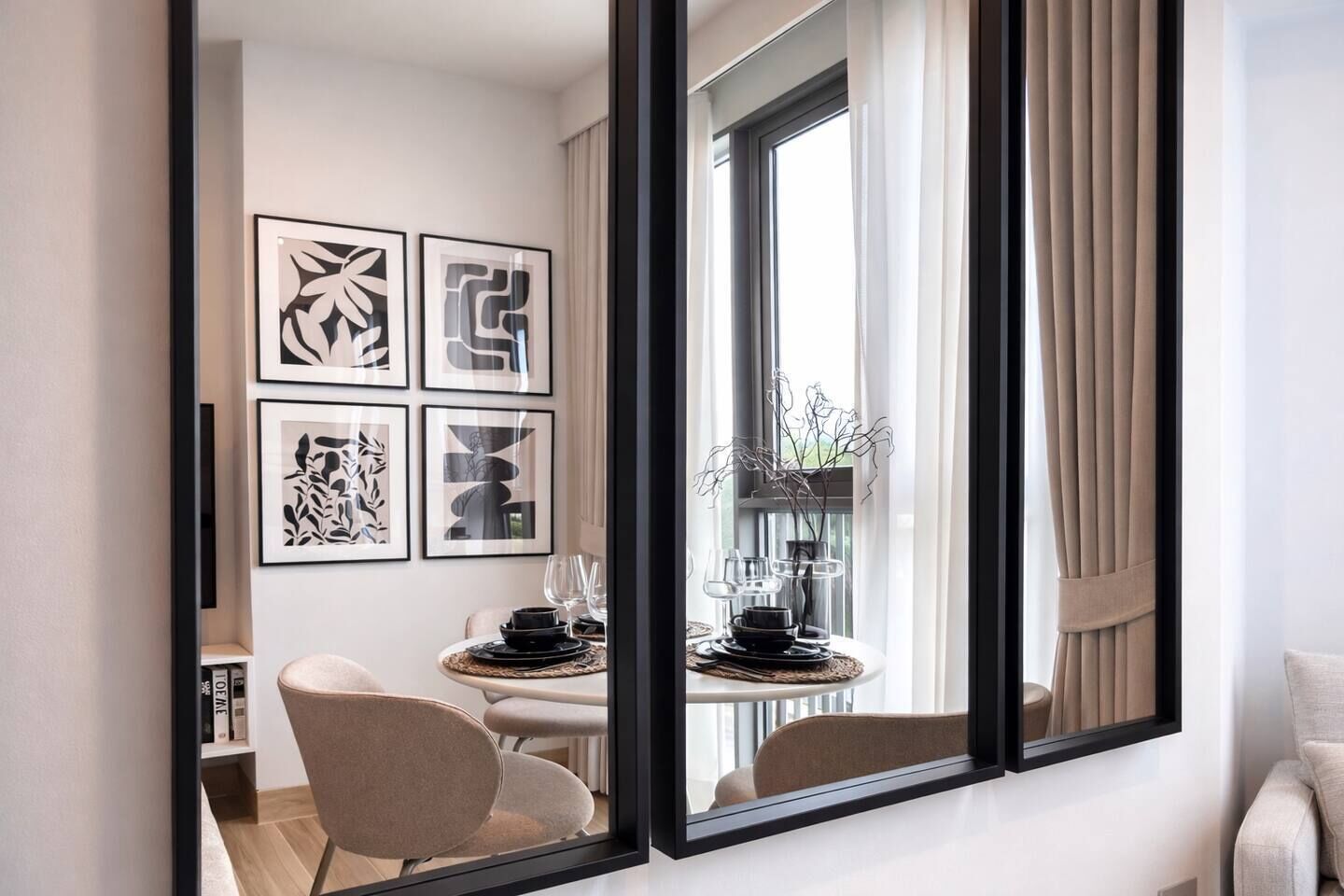 Ein modernes Hotelzimmer mit Essbereich, einem großen Fenster mit Vorhängen und abstrakter Kunst an der Wand.