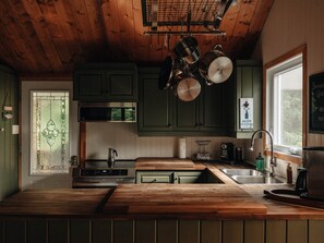 A kitchen with wooden cabinets, a stainless steel sink, and hanging pots.