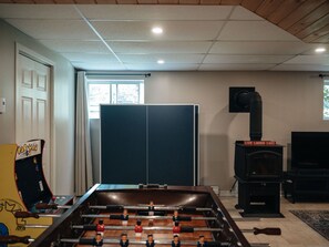 A room with a foosball table, a fireplace, and a television.