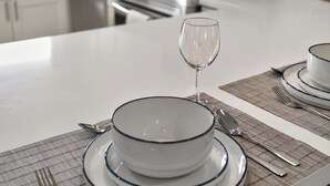 Una cucina moderna con mobili bianchi, un'isola centrale con zona pranzo e un piano cottura a vista.