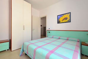 Ein Schlafzimmer mit einem Bett, einem Nachttisch, einem Kleiderschrank und einer Tür zu einem anderen Raum.