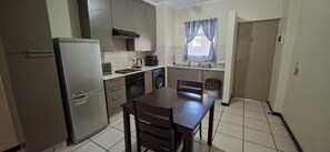 A compact kitchen with a refrigerator, microwave, stove, and sink. - Serene Haven - Peaceful, Secure & Conviniently located apartment (Sandton)