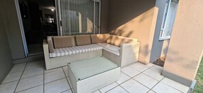 Eine gemütliche Eckterrasse mit einem Korbsessel und passendem Hocker.