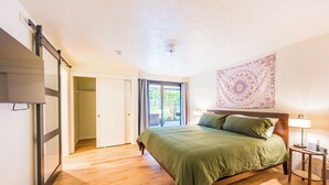 A bedroom with a bed, a nightstand, a lamp, a sliding door, and a ceiling light.