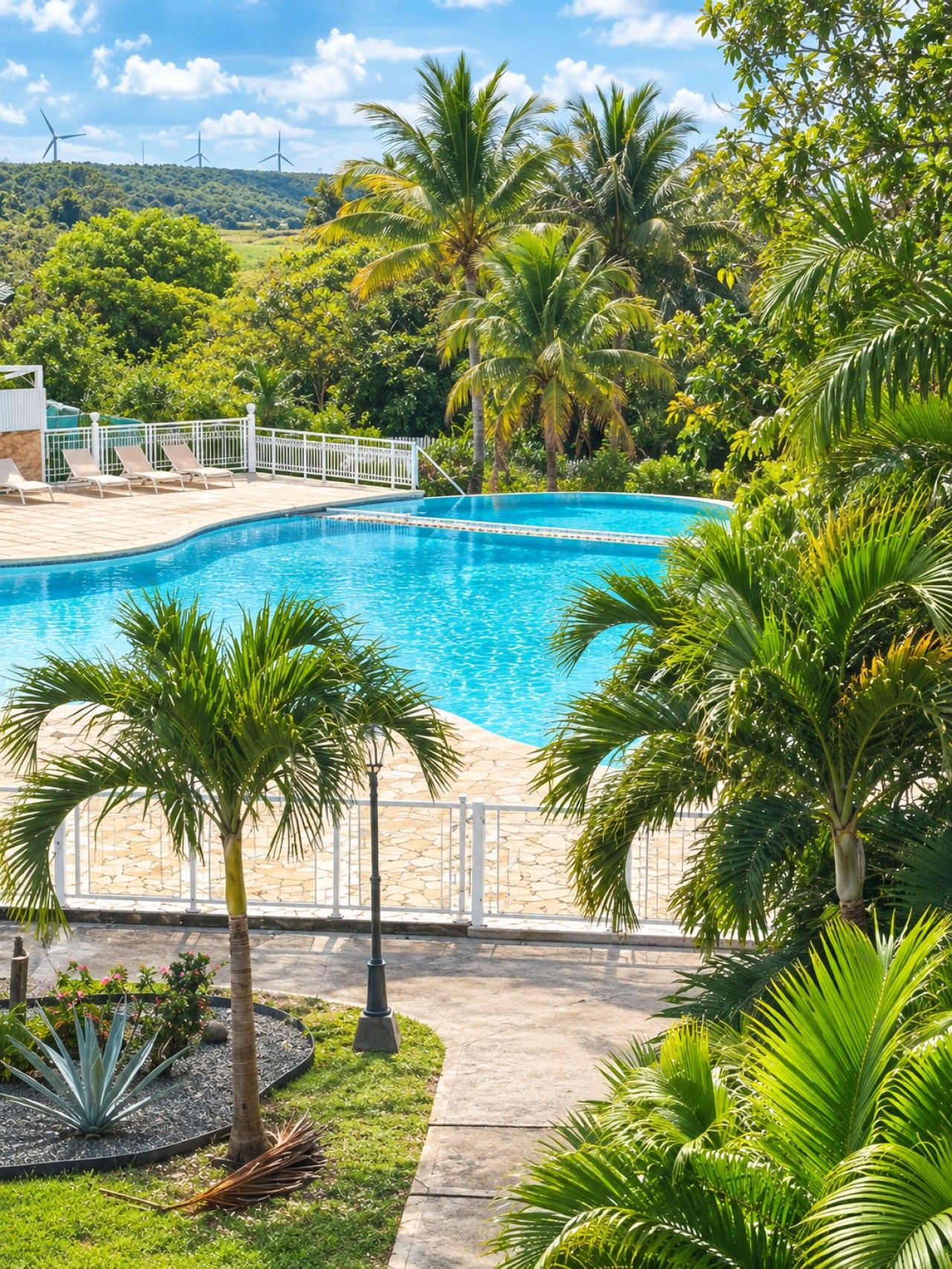 A swimming pool surrounded by palm trees and a white fence.