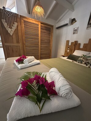 Ein Hotelzimmer mit Bett, Holzschrank, Pendelleuchte und Wandairconditioner.