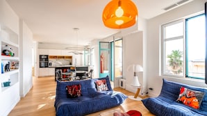 A modern living room with a sofa set, a dining table, and a kitchen in the background. - Contemporary apartment with sea view - Private parking & Private boat (Sainte-Maxime)