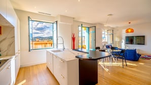 A modern kitchen with a large window, a dining area with a table and chairs, and a living room with a TV. - Contemporary apartment with sea view - Private parking & Private boat (Sainte-Maxime)