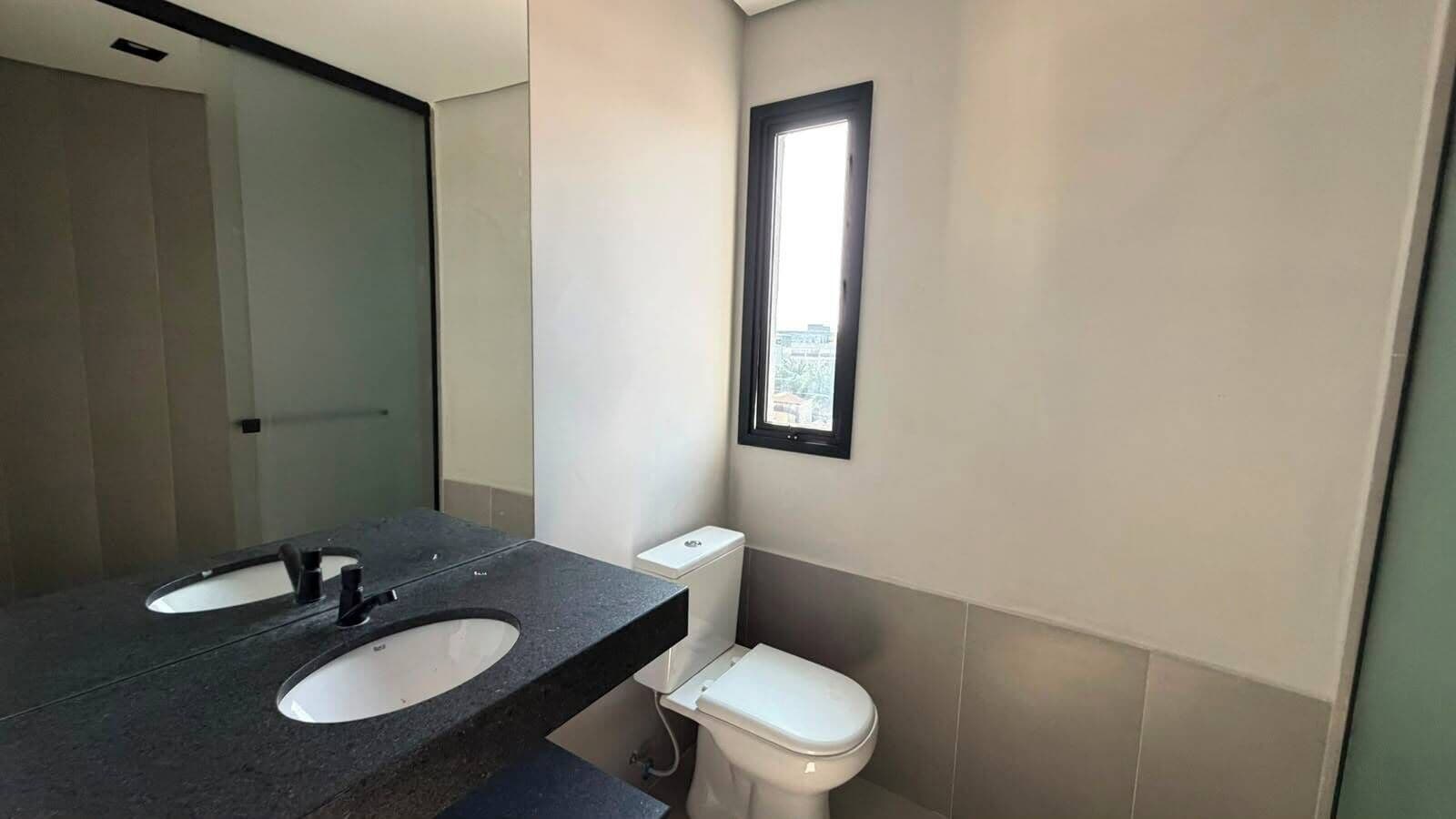Un baño con lavamanos doble, inodoro y ventana que proporciona luz natural.