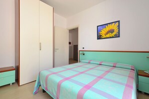 Ein Schlafzimmer mit einem Bett, einem Nachttisch, einem Kleiderschrank und einer Tür zu einem anderen Raum.