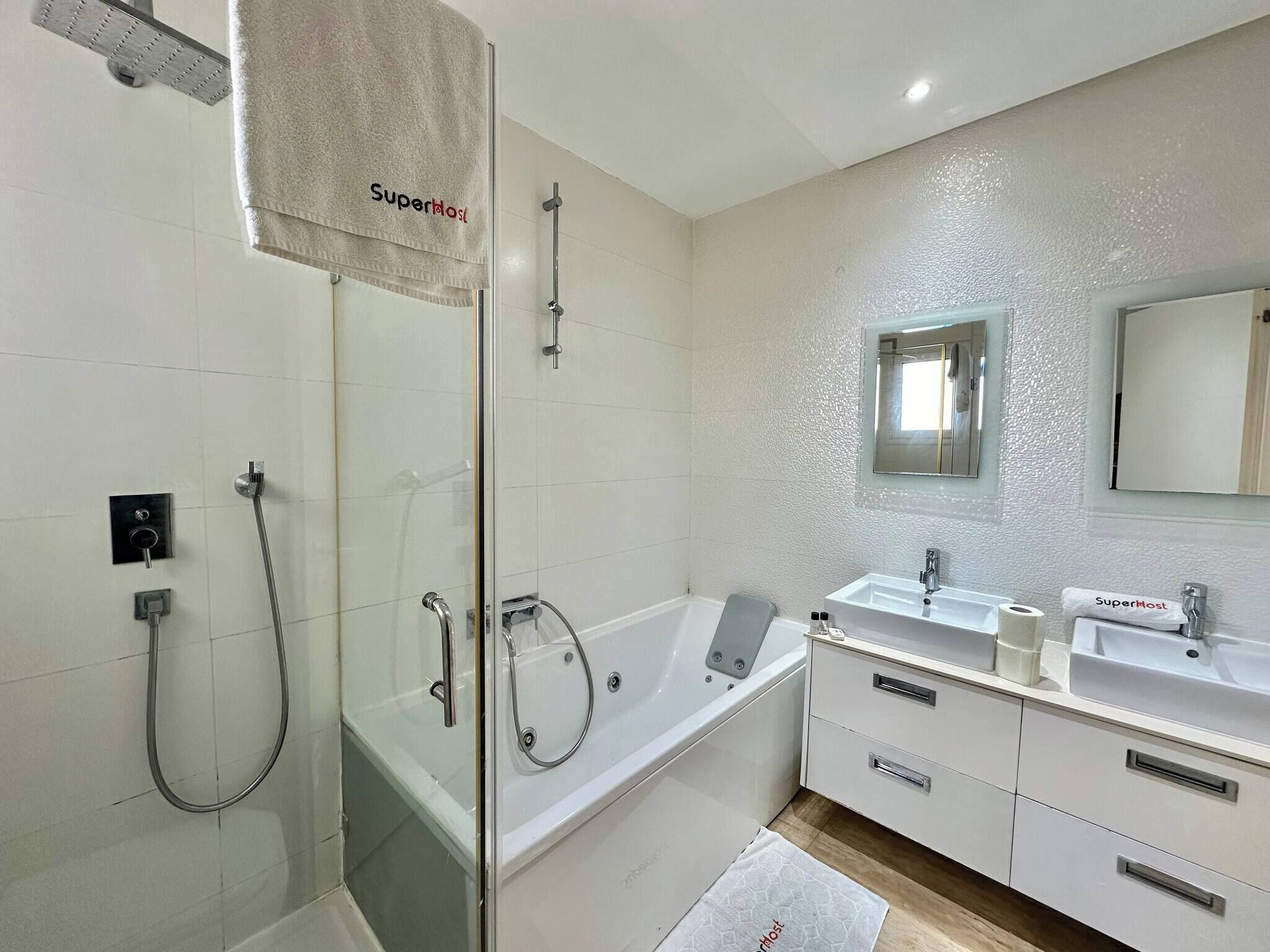 A modern bathroom with a glass-enclosed shower, a bathtub, and a vanity with a mirror.