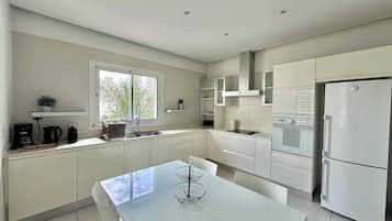 Una cocina moderna con armarios blancos, horno empotrado y refrigerador.