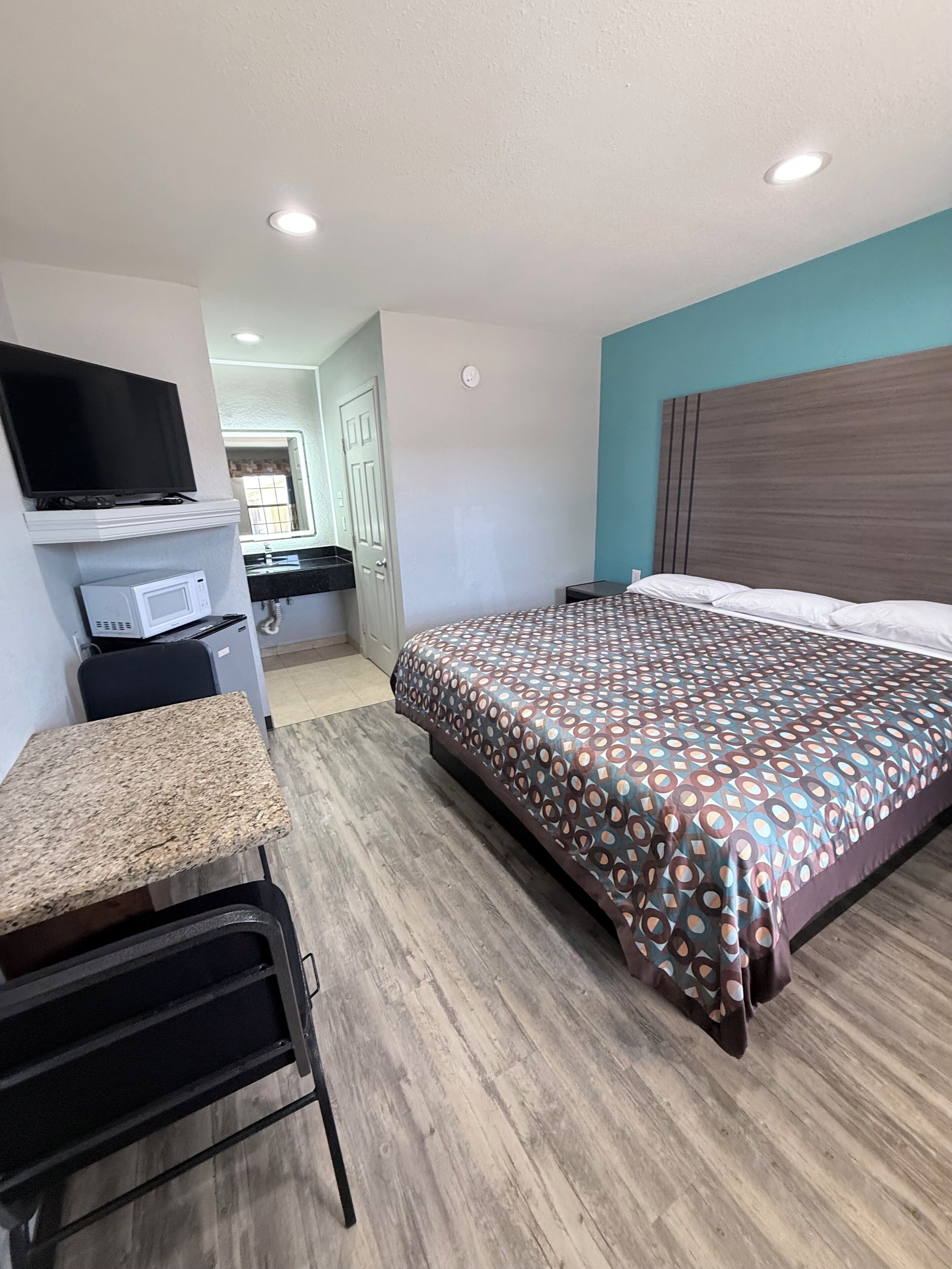 Une chambre d’hôtel comprenant un lit, un bureau avec une télévision, un four à micro-ondes et une porte donnant accès à une salle de bain.