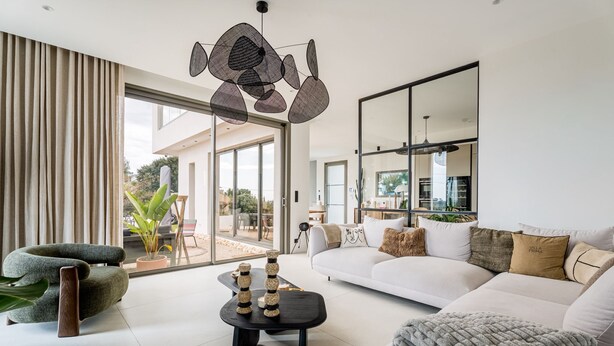 Una sala de estar moderna con un sofá, un sillón, una mesita de centro y un ventanal grande.