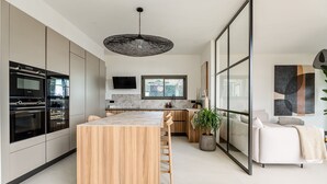 Una cocina moderna con electrodomésticos integrados, una isla central y un comedor con sofá y una planta.