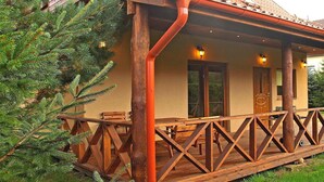 Eine Holzterrasse mit Bänken, eine überdachte Veranda und eine Tür mit Fenster.