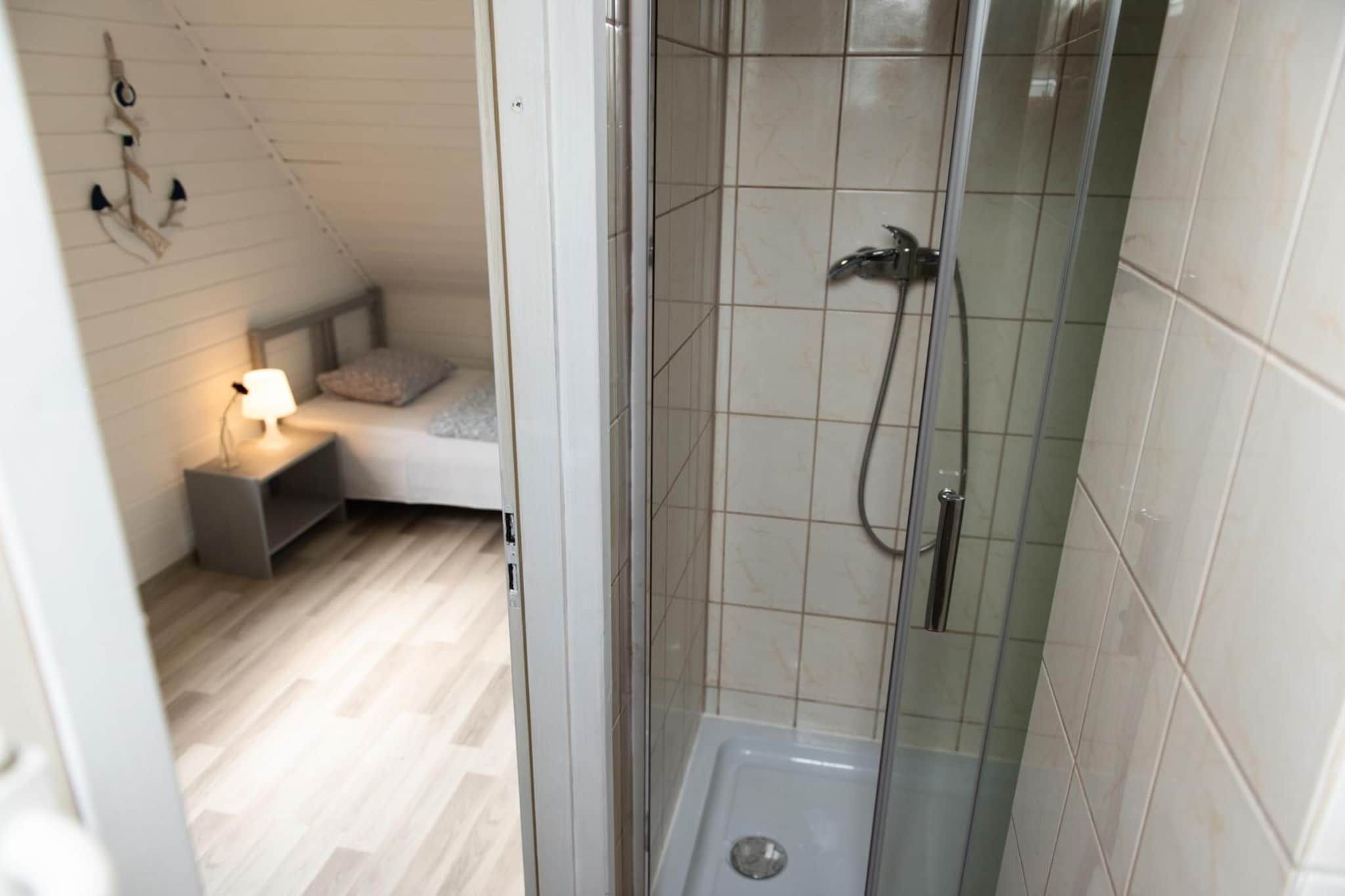 A bathroom with a shower, a toilet, and a bedside table with a lamp.