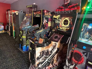 Una fila de máquinas de arcade con la marca 'Terminator' y 'Multi-Arcade', un cartel de 'Glavvy Hill' y una interfaz de juego 'Player'.
