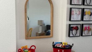 A mirror, a red basket with snacks, and a tray with Hostess Donettes on a wooden console. - Magical Condohotel at Resort Lake Buena Vista (Orlando)