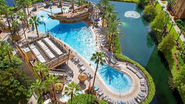 A resort with multiple swimming pools, palm trees, and a large ship-themed structure. - Magical Condohotel at Resort Lake Buena Vista (Orlando)