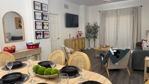 A dining area with a round table set for four, a television, a ceiling fan, and a window with curtains. - Magical Condohotel at Resort Lake Buena Vista (Orlando)
