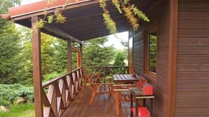 Una terraza de madera con una mesa y sillas, rodeada de follaje.