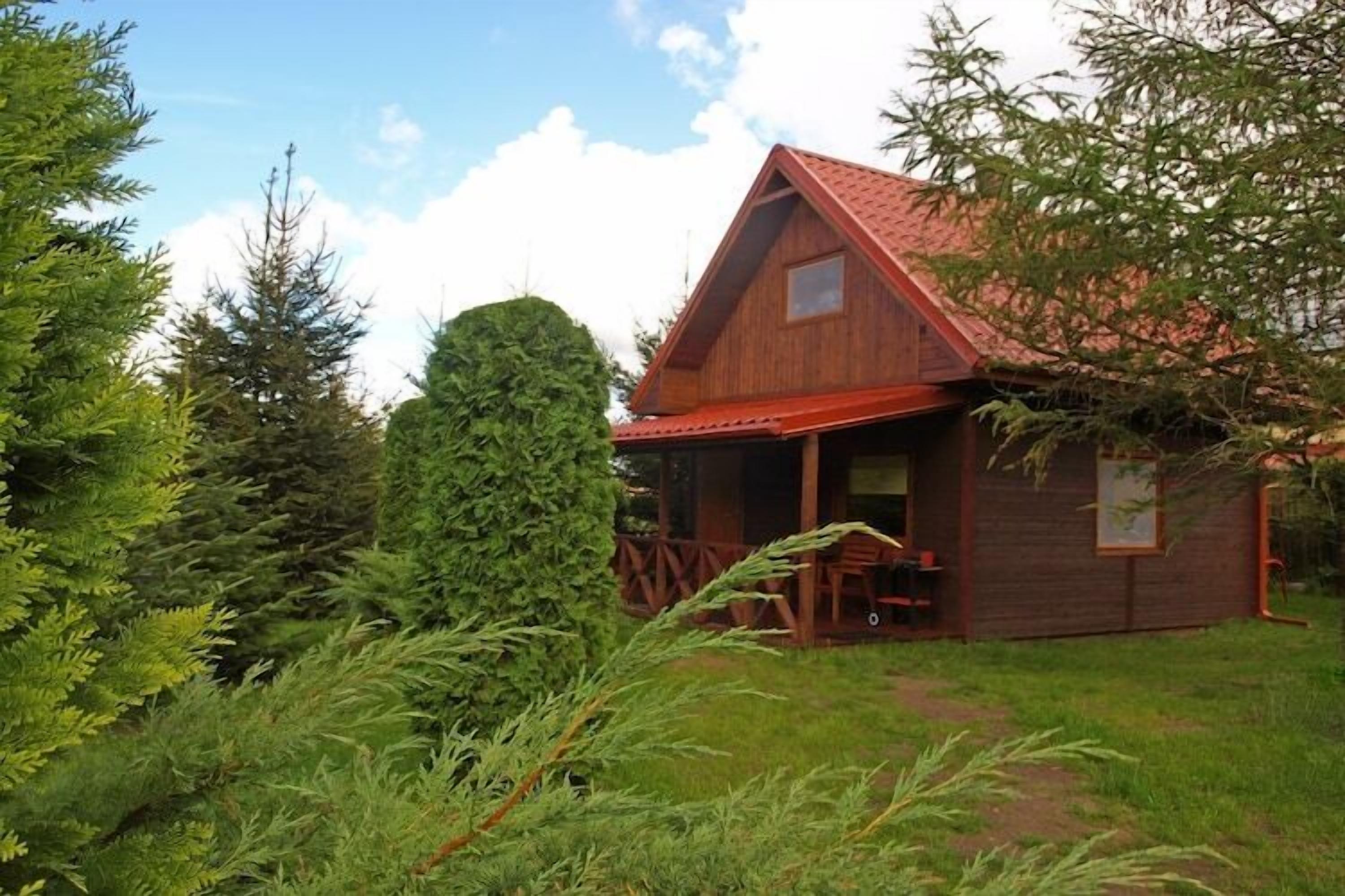 Une cabane en bois avec un toit rouge, entourée d’une végétation luxuriante.