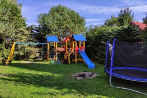 A playground with a slide, swings, and a trampoline. - Holiday home with a fireplace and a large terrace (Kopalino)