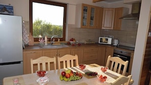 A kitchen with wooden cabinets, a microwave, and a dining table set with fruit. - Large, comfortable holiday home with a garden (Smoldzino)