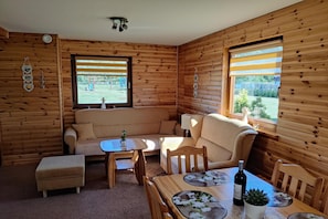 A cozy cabin interior with a sofa, a small table, and a window with blinds. - Large, comfortable holiday home with a garden (Smoldzino)