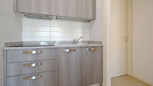 A kitchen with grey cabinets, a stainless steel sink, and a tiled backsplash. - Vacation Flat Near the City Centre (Lignano Sabbiadoro)