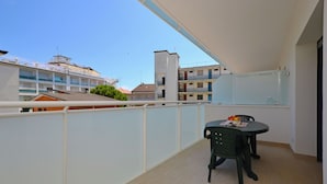A balcony with a table and chairs, a view of surrounding buildings, and a clear sky. - Vacation Flat Near the City Centre (Lignano Sabbiadoro)