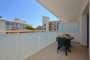 Ein Balkon mit Tisch und Stühlen, Blick auf umliegende Gebäude und einem klaren Himmel.