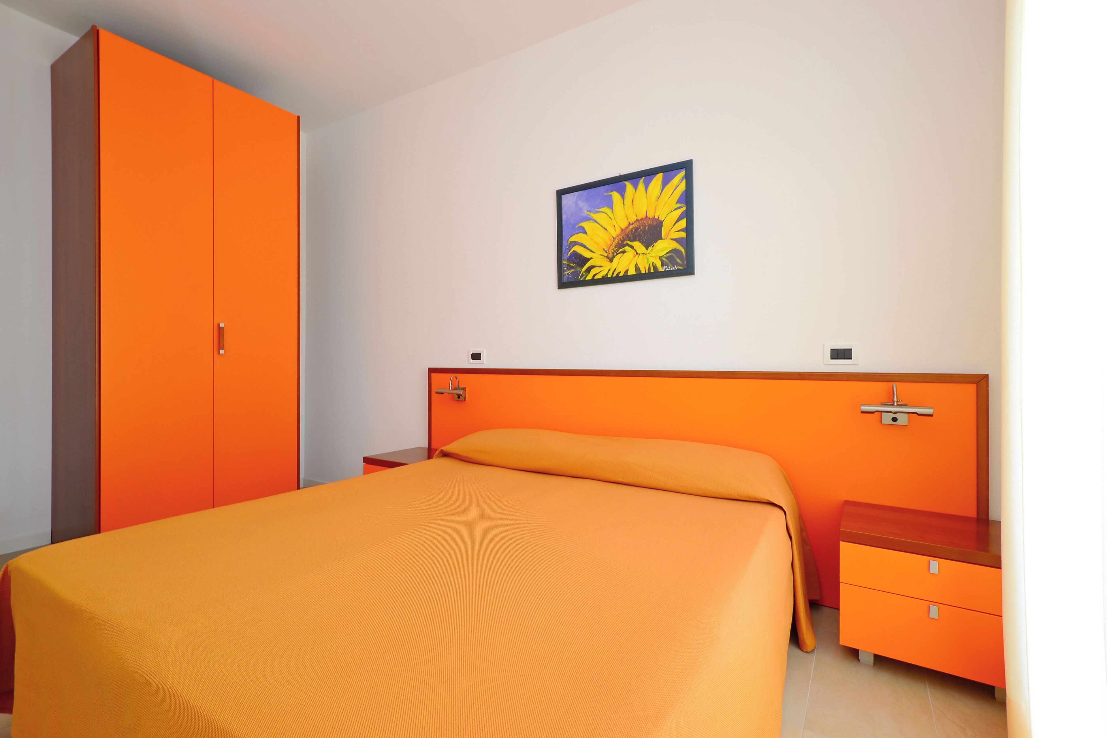 Une chambre à coucher avec un grand lit, une armoire, une table de chevet et un tableau accroché au mur.