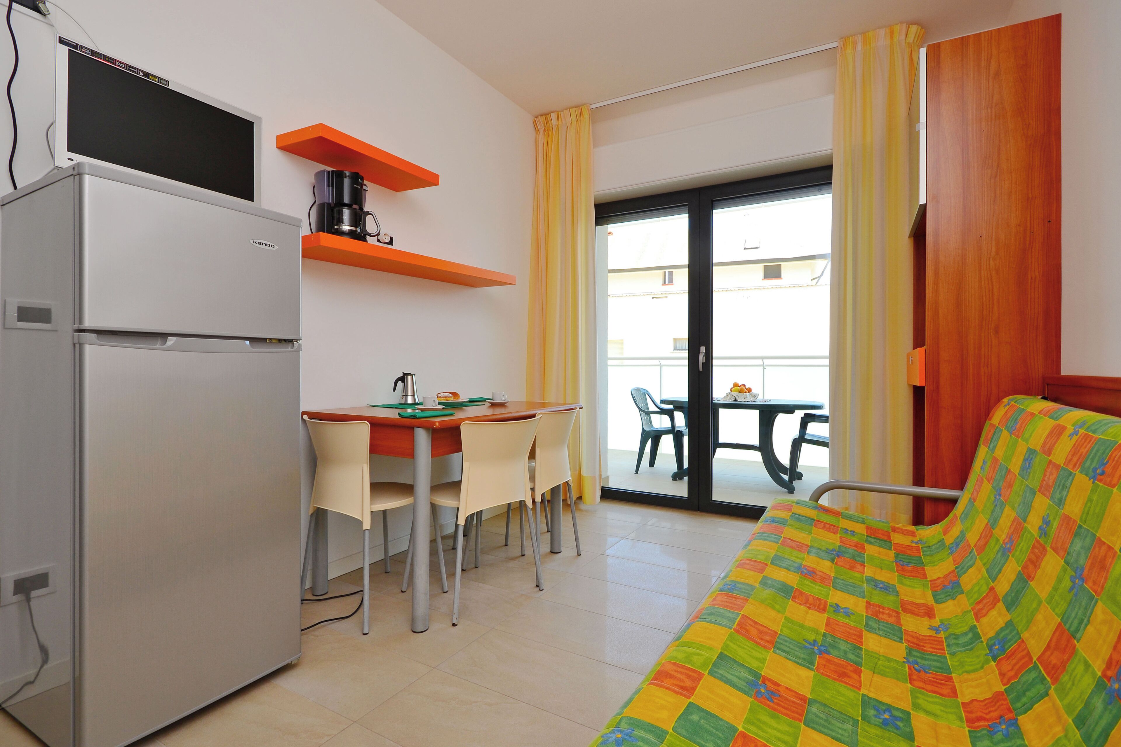 Quarto compacto com cozinha compacta, área de refeições, sofá e varanda com vista.