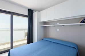 Ein Hotelzimmer mit Bett, einem Vorhangfenster, einem Balkon und eingebauten Regalen.
