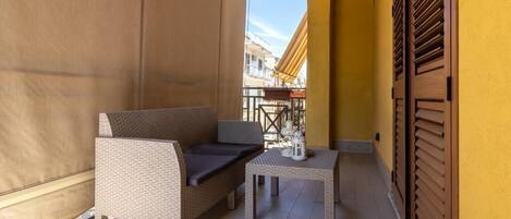 A balcony with a wicker sofa, a small table, and a lantern.