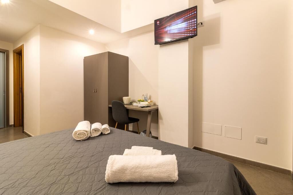Una habitación de hotel con cama, escritorio, televisión y armario.