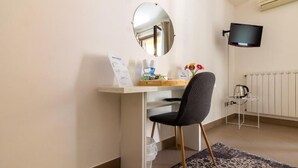 A room with a desk, chair, mirror, flat-screen TV, radiator, and a small table with a kettle. - KANISA MARI E MONTI (Cinisi)