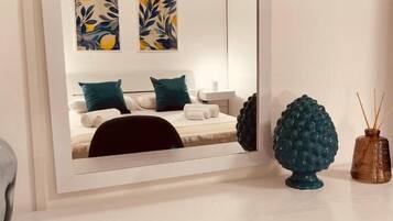 A modern room with a large mirror, a sofa, two abstract paintings, and decorative items on the mantel.