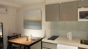 A modern kitchen with a dining table, cabinets, a painting, and a microwave. - Luxury Sunset River View / Quiet & Convenient / Ximen / Monthly Rentals (Taipei City)