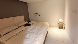A bedroom with a bed, a bedside lamp, and a small table with a lamp. - Luxury Sunset River View / Quiet & Convenient / Ximen / Monthly Rentals (Taipei City)