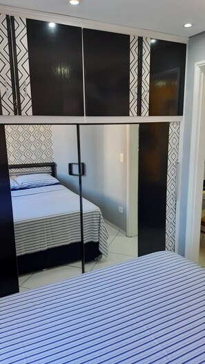 A bedroom with a bed, a wardrobe, and a mirror. - Cozy Studio in Downtown São Paulo. (São Paulo)